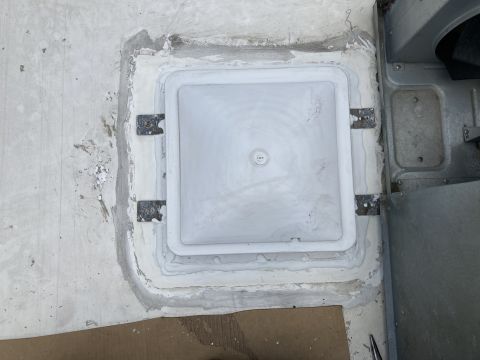 2015 Ford F-550 - A white square vent cover is installed on a flat surface, surrounded by sealant and metal brackets. A portion of a gray metal housing is vi…