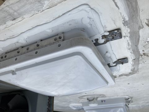2015 Ford F-550 - A close-up view shows a white hinged access panel being installed on the underside of a vehicle, secured with metal brackets and screws. Wh…