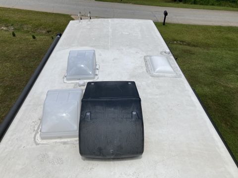 2015 Ford F-550 - The top of an RV roof is shown, featuring several vents and a skylight. A black RV air conditioner unit is prominently displayed in the cen…