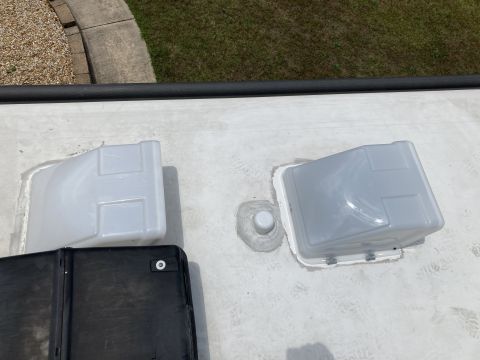 2015 Ford F-550 - Two white vent covers are installed on a white RV roof, with a black cover partially visible in the foreground. A small white pipe fitting…