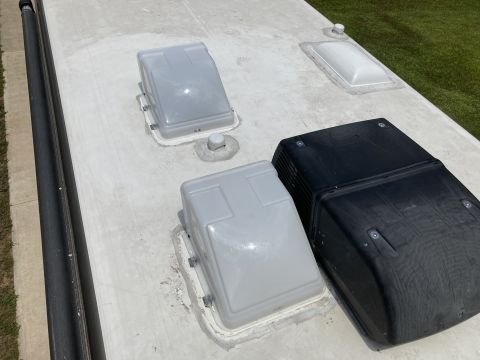 2015 Ford F-550 - The roof of an RV is shown with two gray vent covers, a black air conditioning unit, and a skylight. A portion of an awning is visible alon…
