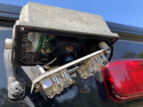 2015 Ford F-550 - A camera housing is mounted on the exterior of a vehicle, with a red taillight visible to the right.