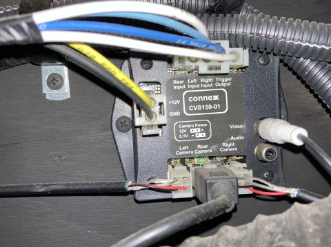 2015 Ford F-550 - A Connex CVS150-01 module is mounted to a dark surface, with various wires connected to it. The module has labels for camera inputs, power,…