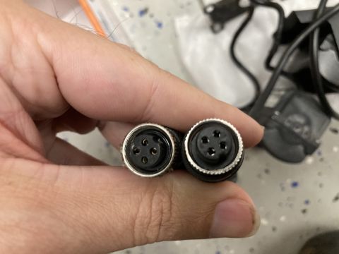 2015 Ford F-550 - A hand holds two circular electrical connectors with four pins each. The connectors appear to be part of a vehicle's wiring harness.