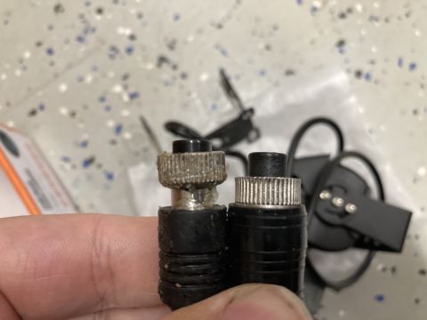 2015 Ford F-550 - A person is holding two black electrical connectors. One connector appears to have corrosion or debris around its metal threaded portion.