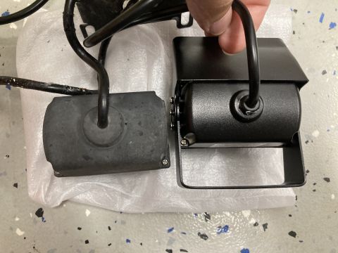 2015 Ford F-550 - Two black electronic devices with wires are shown on a white plastic sheet. One device is rectangular with rounded edges and appears to be…