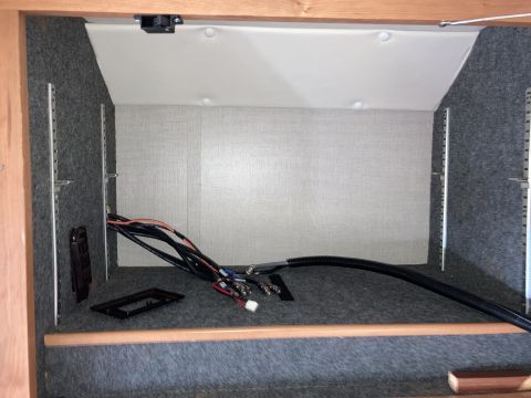 2015 Ford F-550 - Inside a compartment lined with grey carpet, various wires and cables are visible, along with a black plastic mounting bracket. A flexible…