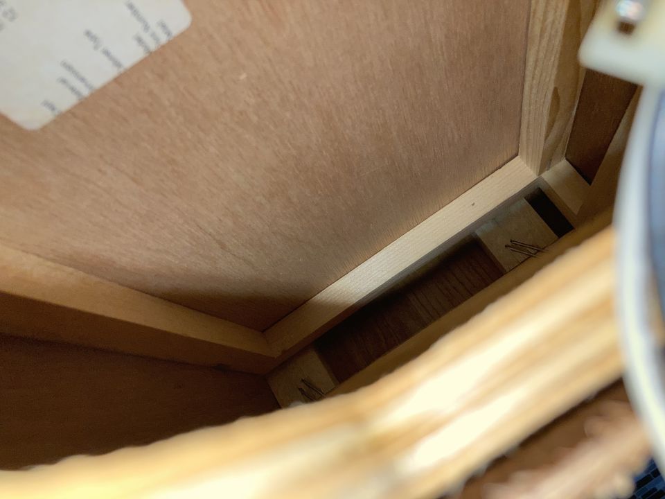 Interior of a wooden box with labels on the inside lid and some visible in the gap
