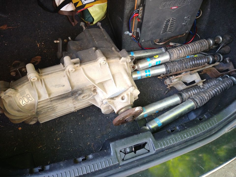 Transfer case and four Bilstein shock absorbers in a vehicle trunk with a Kicker amplifier.
