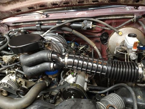 1996 Ford Bronco - Close-up view of the engine bay of a 1996 Ford Bronco, showcasing the intake system and various engine components. The engine is a V8 with…