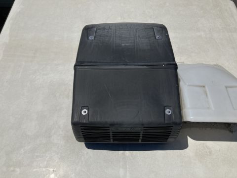 2015 Ford F-550 - black plastic RV rooftop air conditioner shroud with vented sides sitting on a white roof surface.