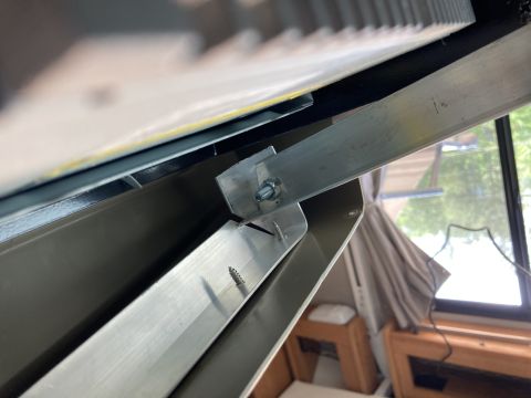 2015 Ford F-550 - A close-up view shows a metal bracket attached with a bolt and nut to an aluminum piece, which is secured by screws to a gray surface. The…