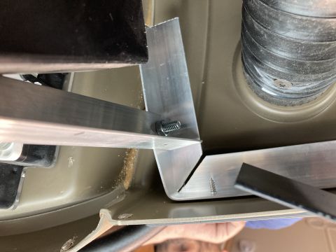 2015 Ford F-550 - Close-up view of custom aluminum brackets being installed with screws and a bolt on the underside of a vehicle. A black corrugated hose is…