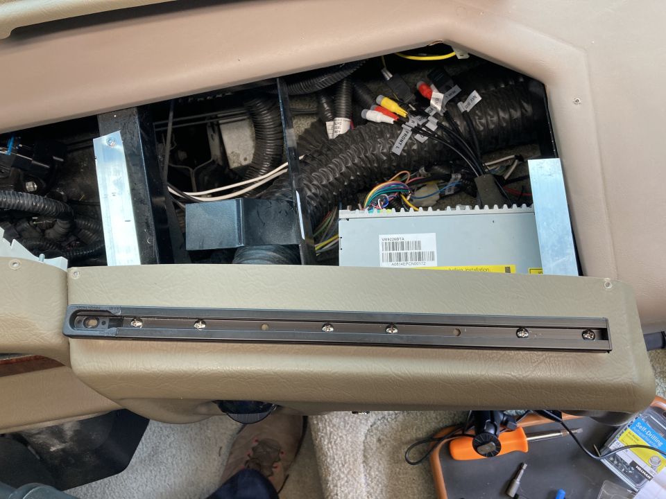 Close-up of vehicle interior dashboard with exposed wiring and a metal mounting rail.