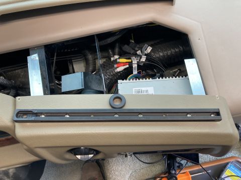 2015 Ford F-550 - A close-up view of the dashboard of a motorhome, showing the interior of a compartment with wiring, a car stereo, and a mounting rail insta…