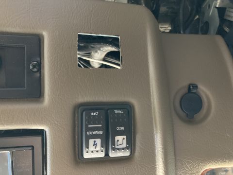2015 Ford F-550 - A close-up view of a tan dashboard panel with two toggle switches labeled "GENERATOR" and "RADIO", a black circular power outlet, and a squ…