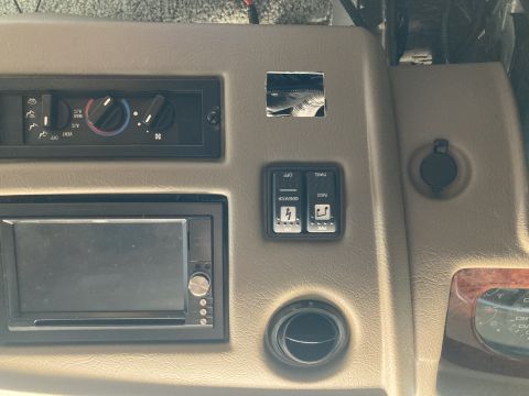 2015 Ford F-550 - The interior dashboard of a motorhome features a car stereo, climate controls, and various switches and a power outlet.