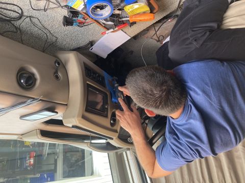 2015 Ford F-550 - A person works on the dashboard of a motorhome, with wires and tools scattered around the area.