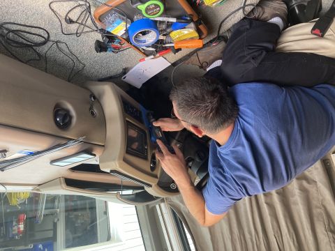 2015 Ford F-550 - A person works on the dashboard of what appears to be an RV, with various tools and wires spread out on the floor and dashboard.