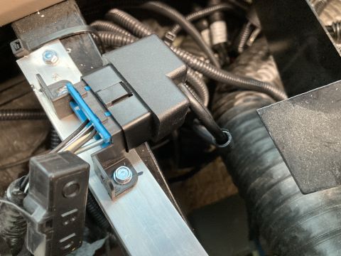 2015 Ford F-550 - A close-up view shows a black electrical connector with a blue locking tab, connected to a wiring harness. The connector is mounted on a si…