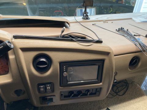 2015 Ford F-550 - The interior dashboard of a motorhome shows a car stereo installed in the center console, with various wires and zip ties scattered on the…