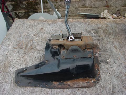 1973 Ford Ranchero - A worn automatic transmission shifter assembly, likely from an older vehicle, sits on a textured wooden surface.