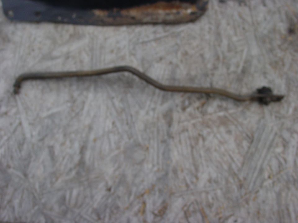 metal rod with a bracket on the end, lying on a textured surface