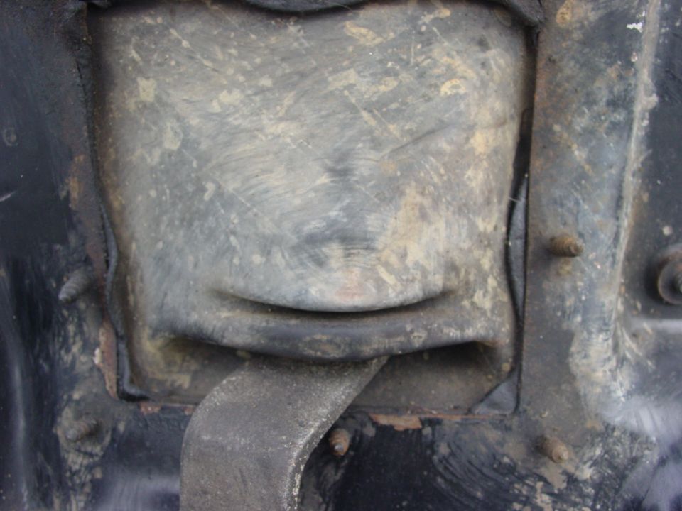 Close-up of a dirty, gray metal part with a curved indentation resembling a smile.