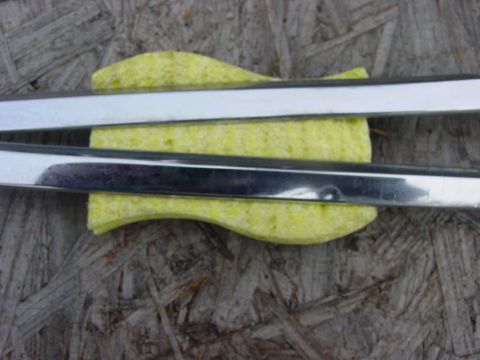 1973 Ford Ranchero - Two chrome trim pieces rest on a yellow sponge, which is placed on a textured wooden surface. The trim pieces appear to be from a vehicle.