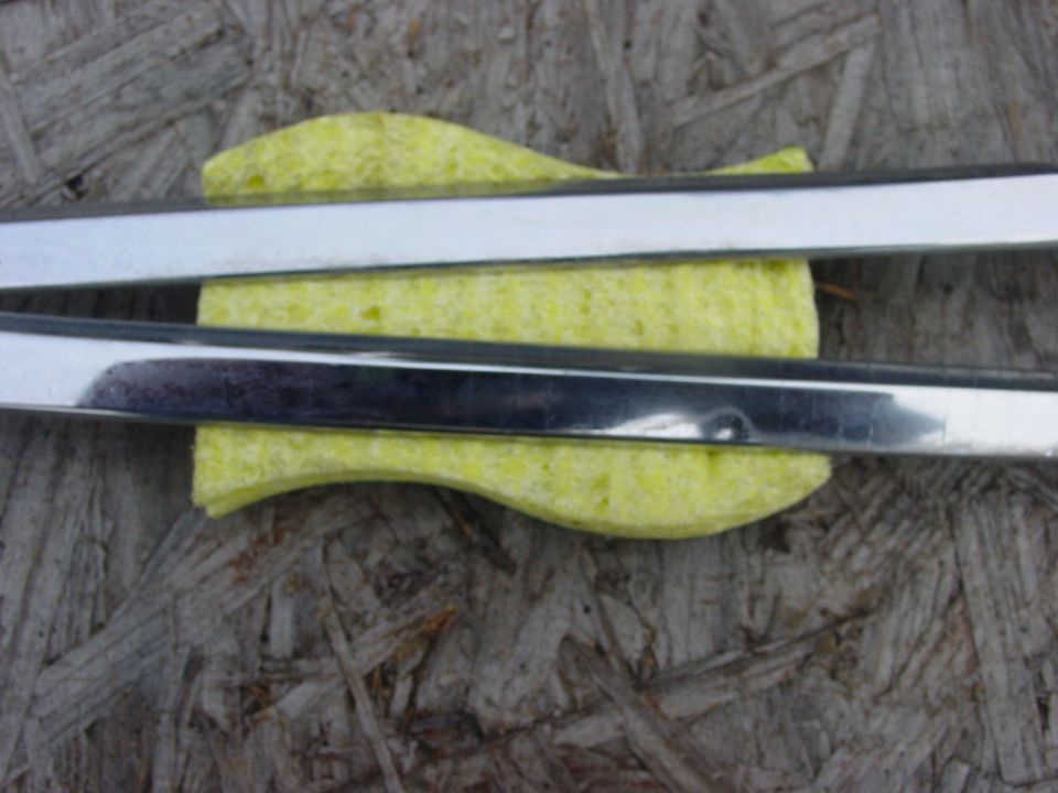 Two chrome trim pieces on a yellow sponge