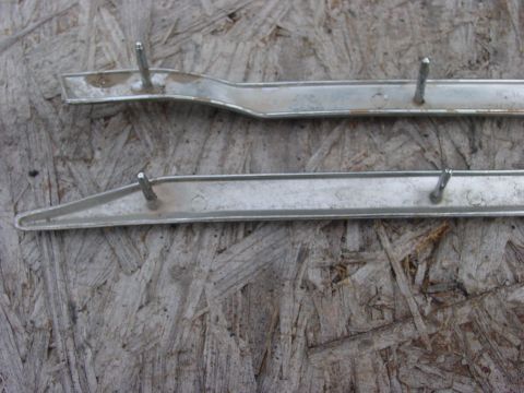 1973 Ford Ranchero - Two chrome trim pieces with mounting studs are shown on a textured wooden surface. The trim pieces appear to be from a vehicle.