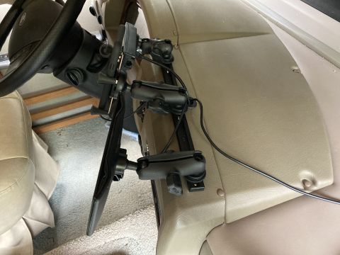 2015 Ford F-550 - A close-up view of a RAM mount system attached to the steering column of a vehicle, holding a tablet device.