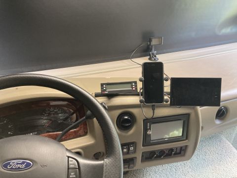 2015 Ford F-550 - The interior of a motorhome dashboard is shown, featuring a steering wheel with a Ford logo, a digital display, a smartphone mounted on a h…