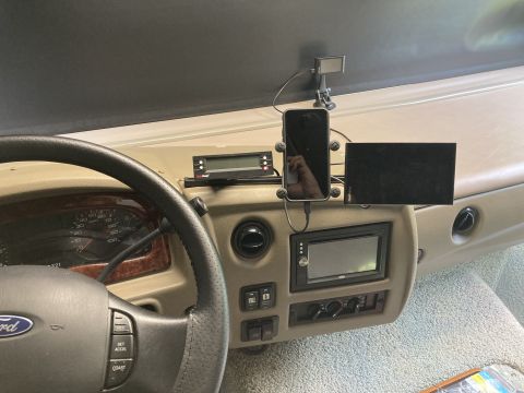 2015 Ford F-550 - The interior dashboard of a motorhome features a steering wheel, instrument cluster, and various mounted electronic devices including a sma…