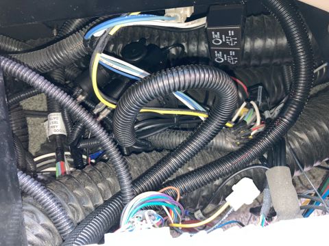 2015 Ford F-550 - A close-up view of a complex wiring harness with multiple black corrugated tubes, various colored wires, and two black electrical relays.