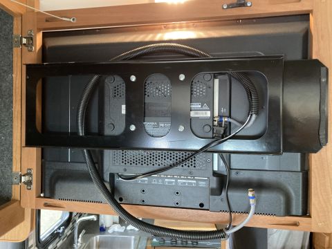 2015 Ford F-550 - The rear of a flat-screen television mounted inside a wooden cabinet. The TV is secured by a black metal bracket, with cables routed throug…