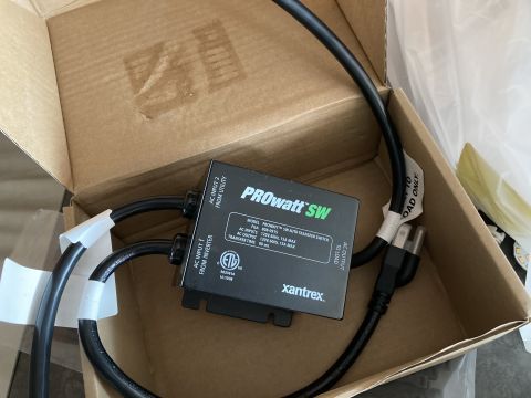 2015 Ford F-550 - A Xantrex ProWatt SW auto-transfer switch is shown inside a cardboard box. The switch has multiple cables connected to it, and labels indic…