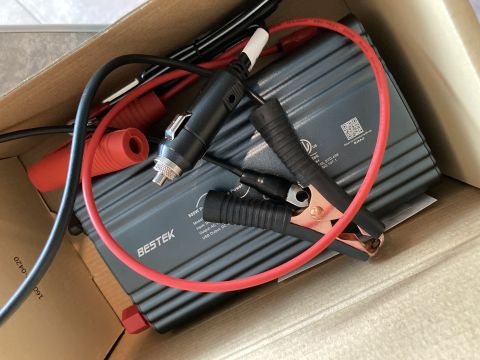 2015 Ford F-550 - A close-up view of a BESTEK power inverter with various cables and connectors, including jumper cable clips and a car cigarette lighter ada…