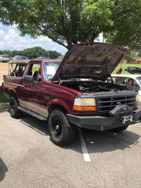 1996 Ford Bronco - A maroon 1996 Ford Bronco with its hood open, revealing the engine bay. The vehicle features a custom aftermarket bumper with a winch and i…