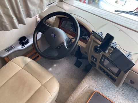 2015 Ford F-550 - The interior driver's side view of an RV shows the steering wheel, dashboard with a mounted phone and GPS, and the driver's seat. The vehic…