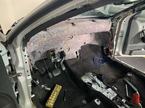 2008 Ford Focus - Interior view of a car with the dashboard removed, showing exposed insulation, wiring, pedals, and floor components. The vehicle appears to…