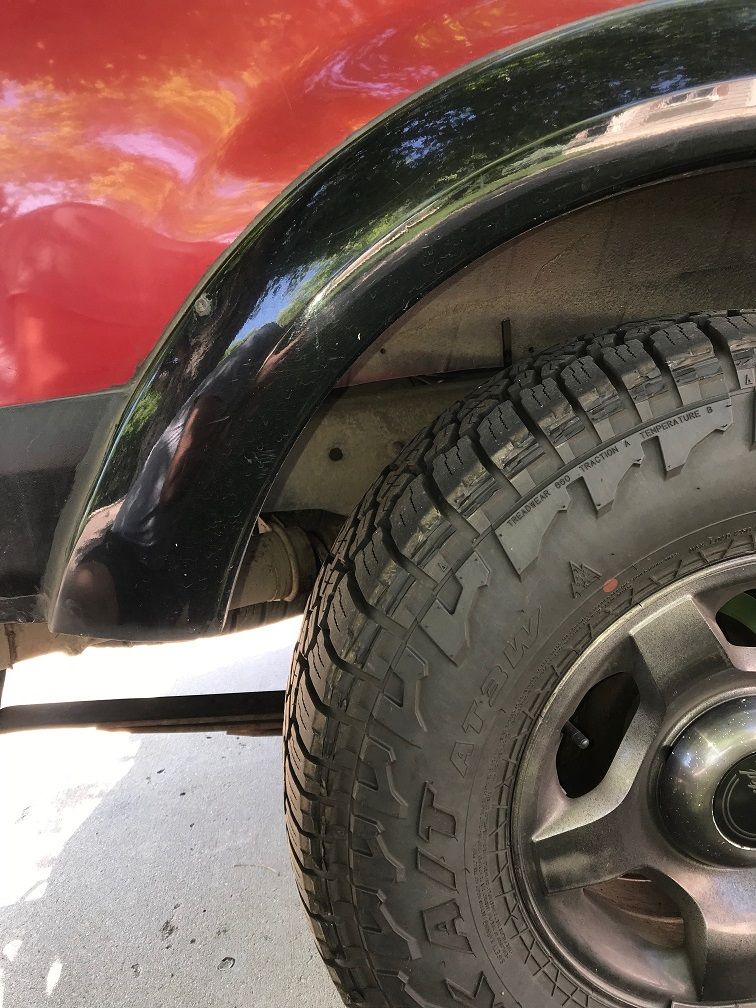 Red Ford Explorer rear fender flare and all-terrain tire.