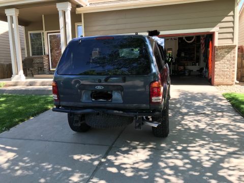 2000 Ford Explorer - A dark-colored SUV is parked in a residential driveway, facing away from the camera.