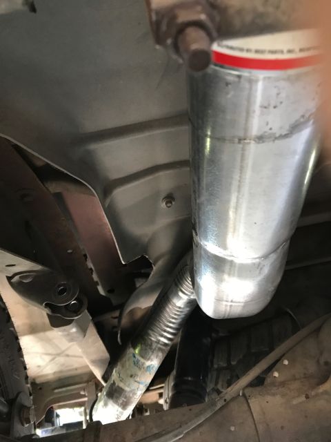 2000 Ford Explorer - Close-up of a vehicle's exhaust system, showing the muffler and piping with some legible text on a label.