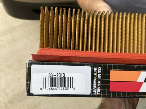 2015 Ford F-550 - A close-up view shows a K&N air filter with a red gasket resting on a black box with a barcode and product number "33-2313". Text on the bo…