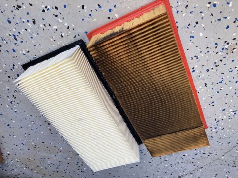 2015 Ford F-550 - A new, white pleated air filter is placed next to a used, dirty, brown pleated air filter with a red frame. Both filters are rectangular.