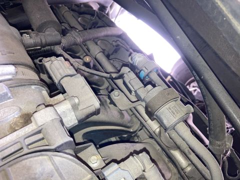 2015 Ford F-550 - A close-up view of engine components in a vehicle, showing various electrical connectors, hoses, and wiring harnesses covered in dust. One…