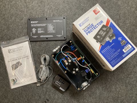2015 Ford F-550 - A Progressive Industries EMS-HW30C hardwired surge protector is laid out with its box, instruction manual, and a remote digital display.