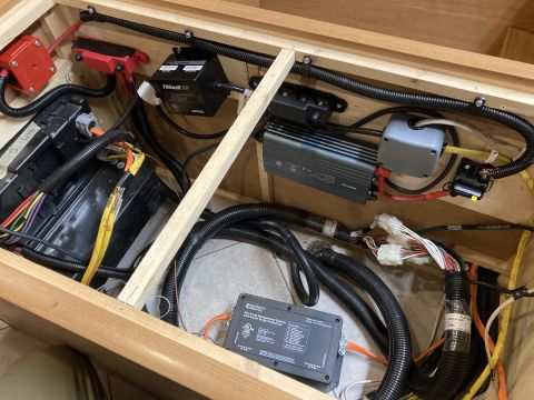 2015 Ford F-550 - Close-up view of the electrical system components, including a surge protector and wiring, housed within a wooden compartment.