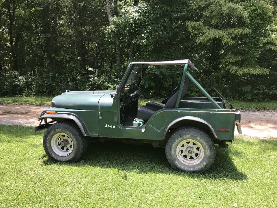 Green 1979 Jeep CJ5 parked on grass with trees in background